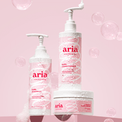 Aria haircare products including curl shampoo, curl conditioner and curl cream on a pink background with bubbles.