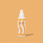 Aria haircare heat spray bottle on a orange background