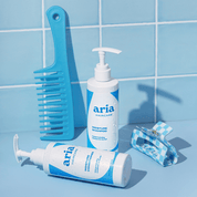 Aria haircare hydrate shampoo and hydrate conditioner with a blue comb and clip on a tiled blue background
