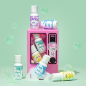 Aria hair care products around a pink vending machine on a light green background with bubbles.