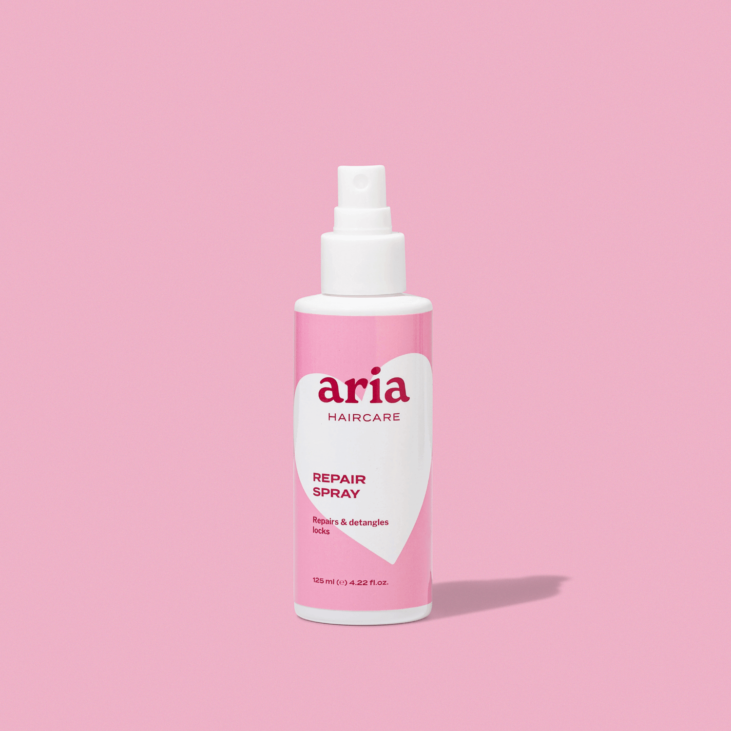 Aria haircare repair spray bottle on a pink background