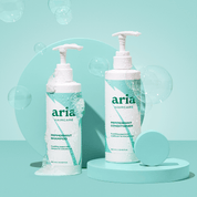 Aria haircare scalp therapy duo peppermint shampoo and conditioner bottles on a light blue background with bubbles