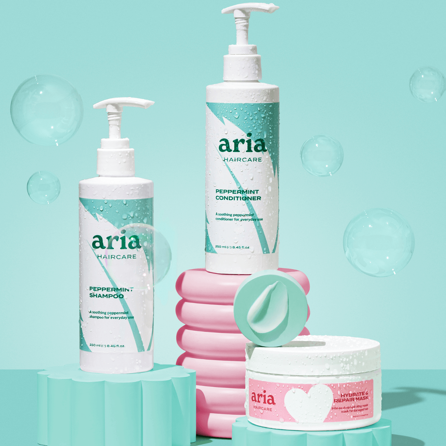 Aria Haircare Scalp Therapy peppermint shampoo, conditioner and hair mask trio on blue background with bubbles